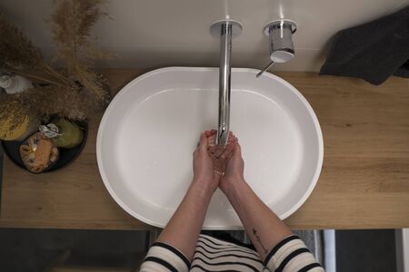 COVID-19 Coronavirus. Woman washing hands with foam soap and hot water at bathroom. Hygiene, preventing coronavirus. Corona Virus pandemic protection by cleaning hands frequently.の写真素材