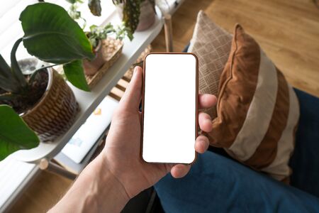 Working on mobile. Taking a picture. Phone in hand with white screen. Blur background. Mockup for mobile design. Close up.の写真素材