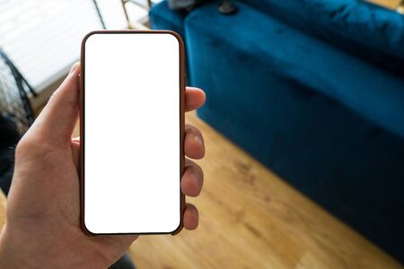 Working on mobile. Taking a picture. Phone in hand with white screen. Blur background. Mockup for...