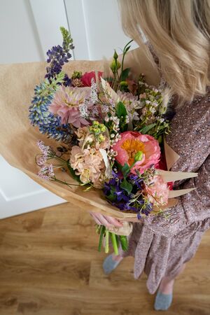 Beautiful bouquet of mixed blossoming fresh flowers in woman hands. Florist with delicate colorful boho style bouquet of peony, gillyflower, eustoma, clove branch, dill, sea lavender, gerberaの写真素材