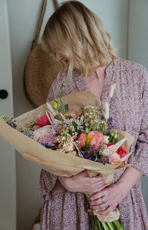 Beautiful bouquet of mixed blossoming fresh flowers in woman hands. Florist with delicate colorful boho style bouquet of peony, gillyflower, eustoma, clove branch, dill, sea lavender, gerberaの写真素材