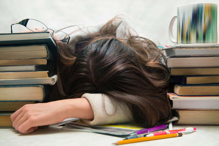Student tired of doing homework studying with pen asleep on open books, isolated.の写真素材