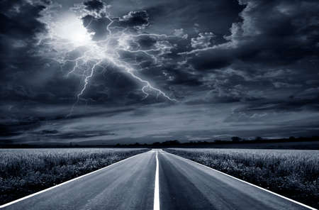 paved road through a field of wheat at night. Stormの写真素材