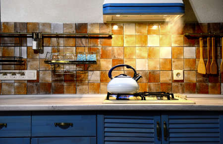new metal whistling kettle boiling in the kitchen. The modern kitchen is blue.の写真素材