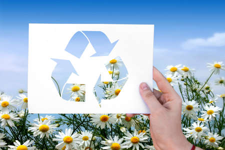 Ecology sign on white sheet on grass background in handの写真素材