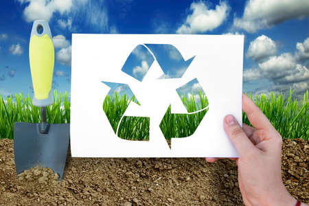 Ecology sign on white sheet on grass background in hand