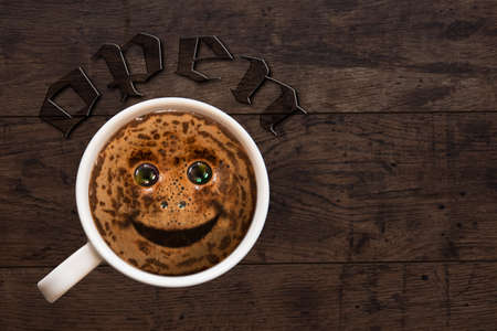 Fragrant black coffee in a porcelain cup on a background of wood with a smileの写真素材