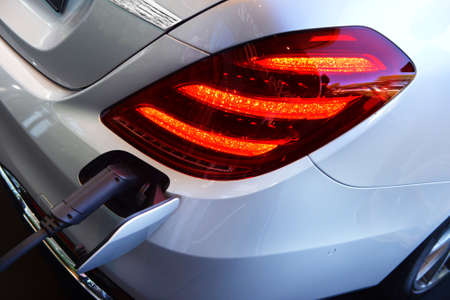 Modern electric car in white on a charge from the mains. Environmentally friendly, transportation of...