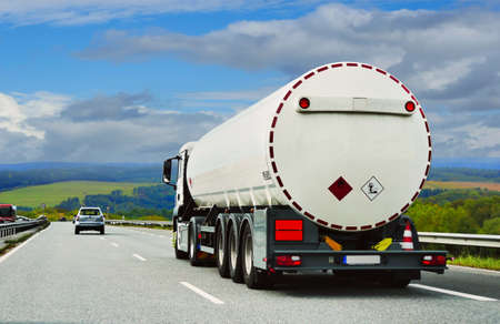 a fuel truck is driving along a beautiful road among fields, forests, and meadows. West Germany. autumnの写真素材