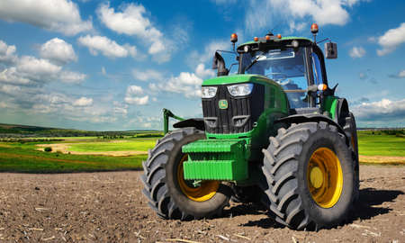 Russia, Krasnodar region, Kushevsky district.16.10.2018.   Modern, green tractor in the spring field work on the background of a beautiful rural landscape.のeditorial素材