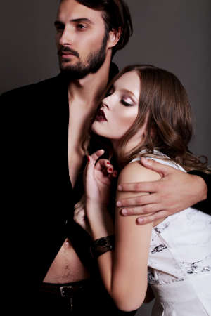 Fashion studio photo of sexy brown-haired woman and brunette man dressed in black and white clothes,hugging and dreamingの写真素材