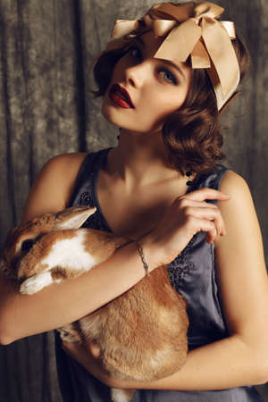 fashion studio photo of beautiful young girl with dark short hair wears retro clothes, holding a...