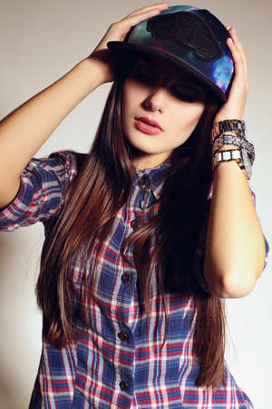 fashion studio photo of beautiful young woman with long dark hair wears casual plaid shirt and capの写真素材