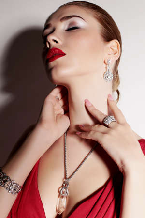 fashion studio photo of gorgeous sensual woman with elegant hairstyle,wears red dress and bijouの写真素材