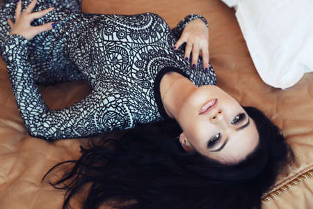 fashion interior photo of sexy beautiful girl with long dark hair wears elegant dress,posing in bedroomの写真素材