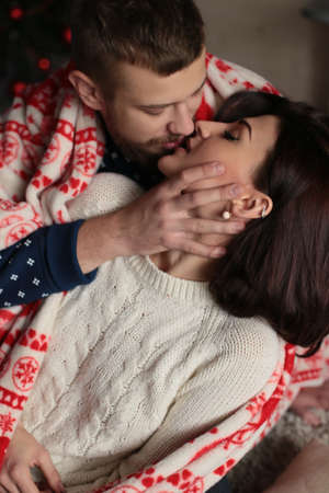 holiday Christmas photo of beautiful tender couple in warm clothes and covered cozy plaid con ornamentの写真素材