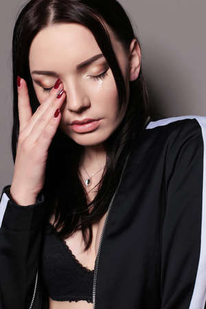 fashion studio portrait of beautiful young woman with dark straight hair, with tears in eyesの写真素材