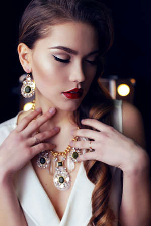 fashion interior photo of gorgeous woman with long dark curly hair wears luxurious necklace and elegant dressの写真素材