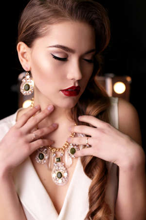 fashion interior photo of gorgeous woman with long dark curly hair wears luxurious necklace and elegant dressの写真素材