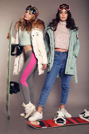 fashion studio photo of two beautiful skier girls wear ski equipmentの写真素材