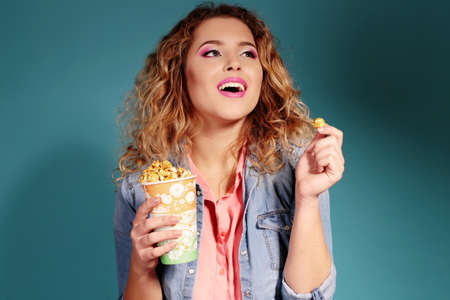 fashion photo of gorgeous woman with blond hair eating popcorn