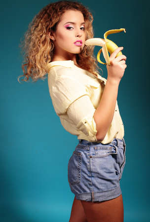 fashion photo of beautiful woman with dark hair eating banana