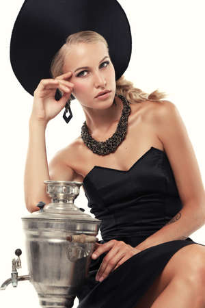 fashion studio photo of gorgeous woman with blond hair in russian national hat with samovarの写真素材