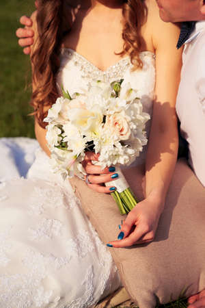 fashion outdoor photo of beautiful couple  in wedding dress, posing in garden. wedding bouquet on focusの写真素材