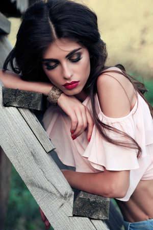 fashion outdoor photo of gorgeous sexy woman with dark curly hair in elegant clothes posing outdoorの写真素材