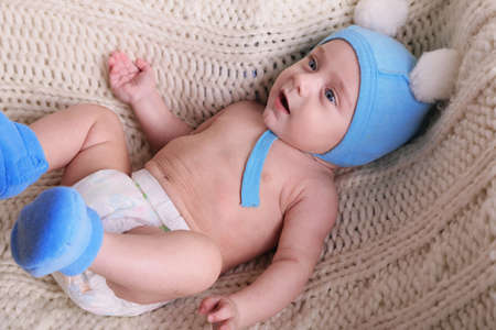 interior photo of cute little baby in warm cozy hat and socks, wears diapers