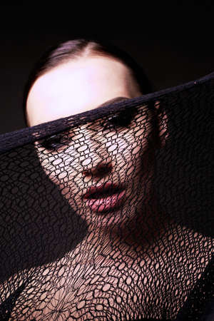 fashion studio portrait of gorgeous sensual woman with dark hair with transparent veil on faceの写真素材