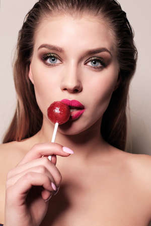 fashion studio photo of beautiful young woman with dark hair with lollipopの写真素材