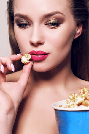 fashion studio photo of beautiful young woman with dark hair posing with popcorn bucketの写真素材