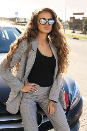 fashion outdoor photo of beautiful sexy woman in elegant clothes posing in luxurious carの写真素材