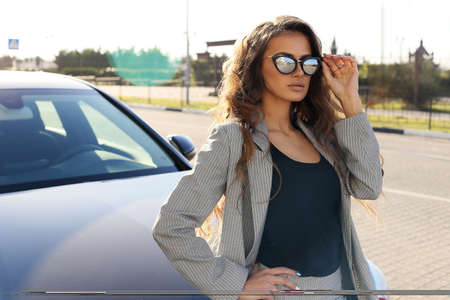 fashion outdoor photo of beautiful sexy woman in elegant clothes posing in luxurious carの写真素材