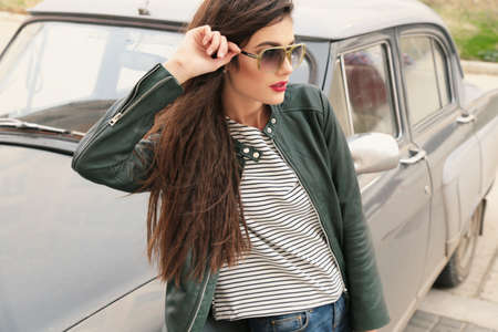 fashion outdoor photo of beautiful girl with dark hair in casual clothes posing near autoの写真素材
