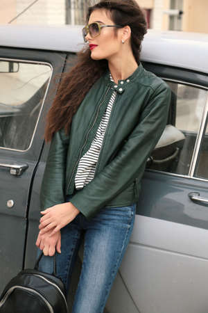 fashion outdoor photo of beautiful girl with dark hair in casual clothes posing near autoの写真素材