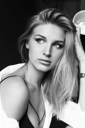 fashion photo of beautiful girl with blond hair in lingerie and white shirt posing in studio