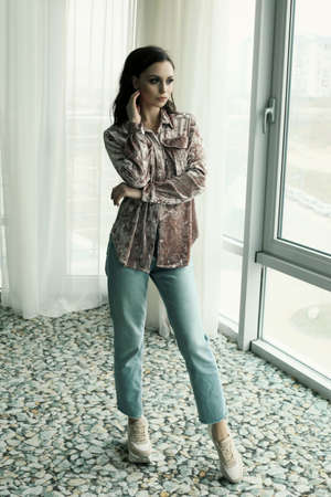 fashion interior photo of beautiful young woman with dark hair in casual jeans clothes