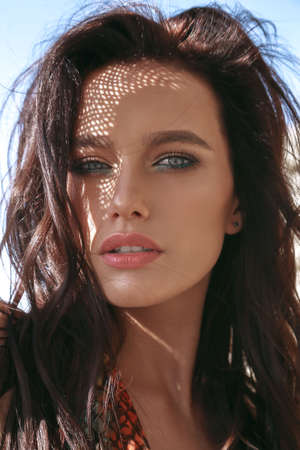 fashion outdoor photo of beautiful sexy woman with dark hair in elegant swimming suit relaxing on summer beachの写真素材