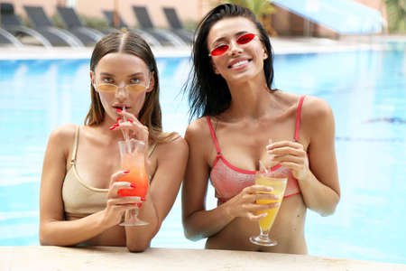 fashion outdoor photo of two beautiful sexy girls in elegant swimming suit relaxing near swimming pool in luxurious villaの写真素材