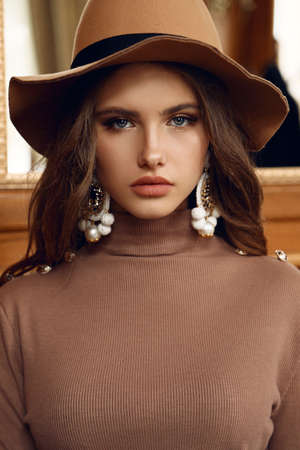 fashion interior photo of beautiful woman with dark hair in elegant clothes and har sitting in cafeの写真素材
