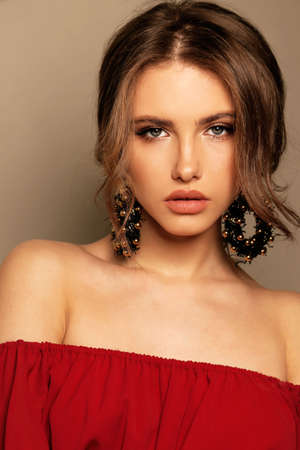 fashion studio portrait of beautiful sexy woman with dark hair in elegant dress with earrings