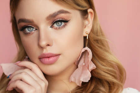 fashion photo of beautiful young woman with blond natural hair and light makeup posing at studio