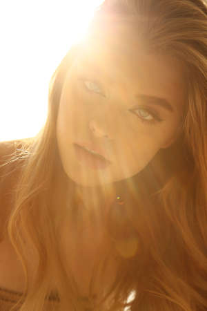 fashion photo of beautiful young woman with blond natural hair and light makeup posing at studio
