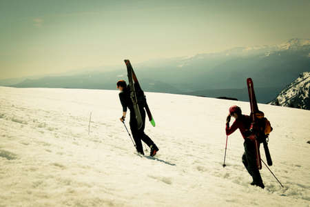 Skiers climbing snowy mountain slope の写真素材
