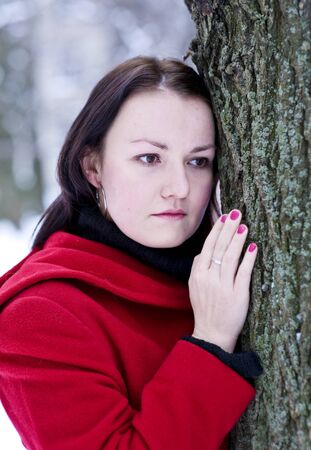 Sad young beautiful girl in the red coatの写真素材