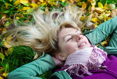 Blond beautiful woman in scarf lying on the grassの写真素材