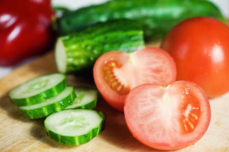 Fresh tomatoes, cucumbers and pepper on the cutting boardの写真素材