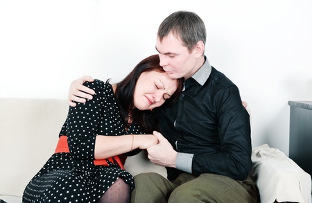 Man comforting her woman on the sofa